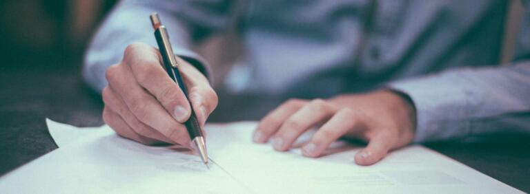 hands writing on paper on table