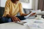 Close up of a mid adult woman checking her energy bills at home, sitting in her living room