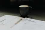 coffee mug on table next to tax books