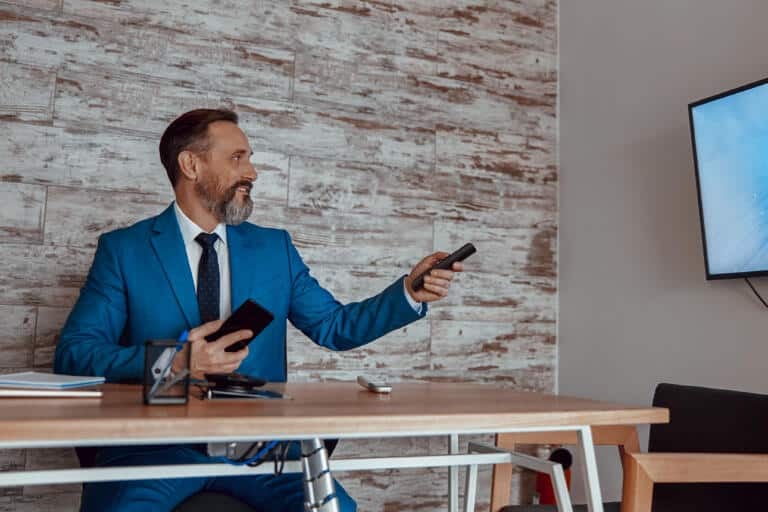 Happy bearded businessman holding phone and console after switching accountant